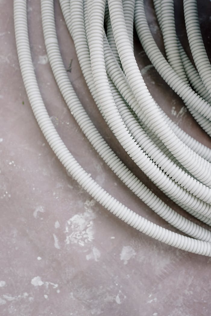 services-03 Close-up of coiled white electrical wire on a rough, textured concrete surface.